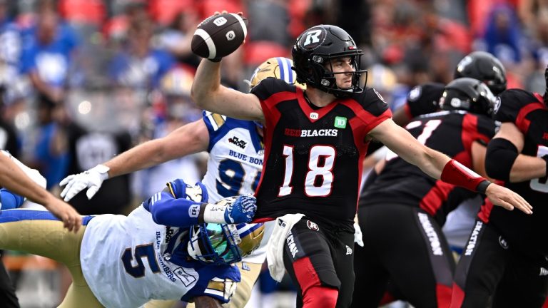 Winnipeg Blue Bombers defensive end Willie Jefferson (5) grabs onto the jersey of Ottawa Redblacks quarterback Dustin Crum (18) as he attempts to throw the ball, during first half CFL football action in Ottawa on Saturday, July 15, 2023. (Justin Tang/THE CANADIAN PRESS)