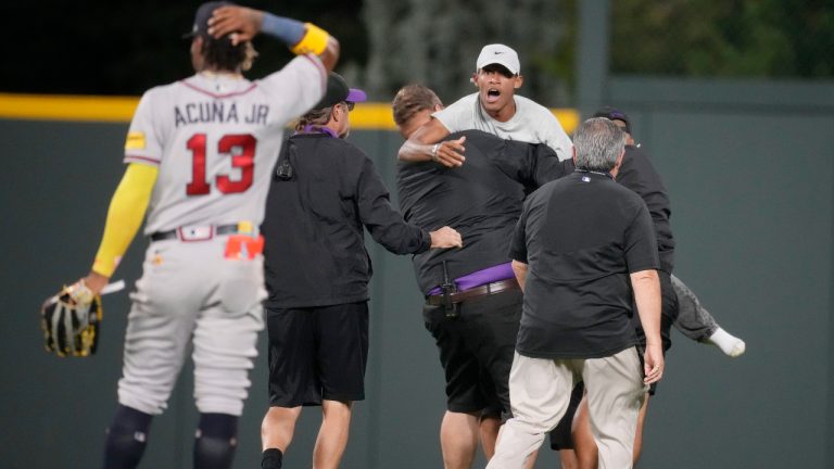 Field guards haul away one of two fans who approached Atlanta Braves right fielder Ronald Acuna Jr. (13) before the bottom of the seventh inning of a baseball game against the Colorado Rockies, Monday, Aug. 28, 2023, in Denver. (David Zalubowski/AP)