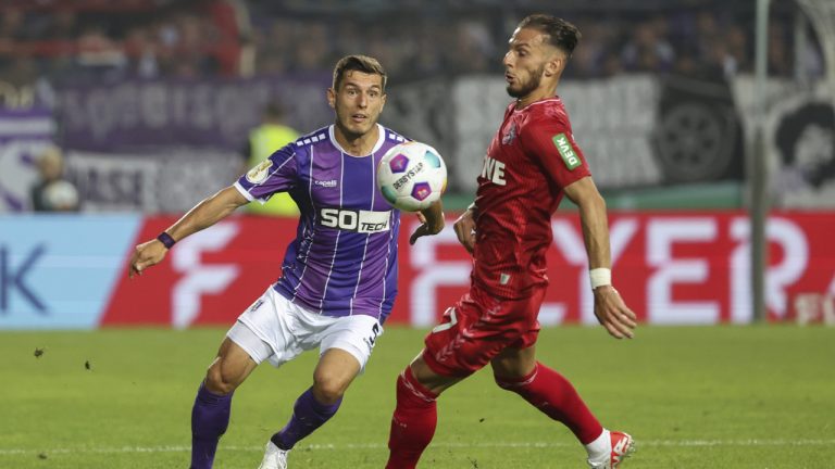 Osnabruck's Bashkim Ajdini, left, and Cologne's Leart Paqarada battle for the ball during the German Soccer Cup between Osnabruck and Koln at Bremer Brucke, Osnabrück, Germany, Monday Aug. 14, 2023. (Friso Gentsch/dpa via AP)