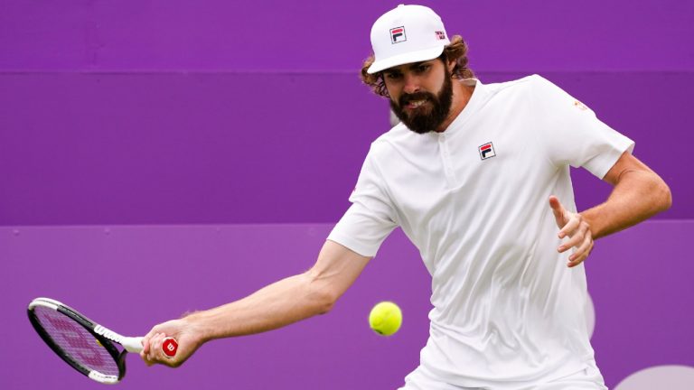 Reilly Opelka of the US returns the ball to Alex De Minaur of Australia, during their single tennis match at Queens Club tournament, in London, Monday, June 13, 2022. (/Alberto Pezzali/AP)