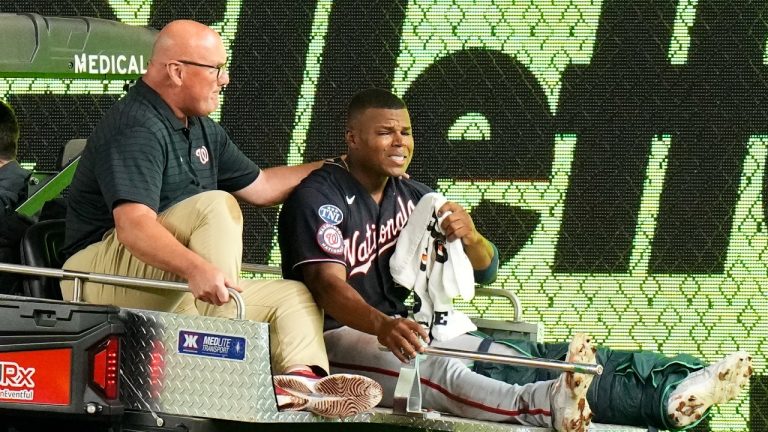 Washington Nationals left fielder Stone Garrett, right, is comforted by a trainer as he is carted off the field with an injury. (Frank Franklin II/AP)