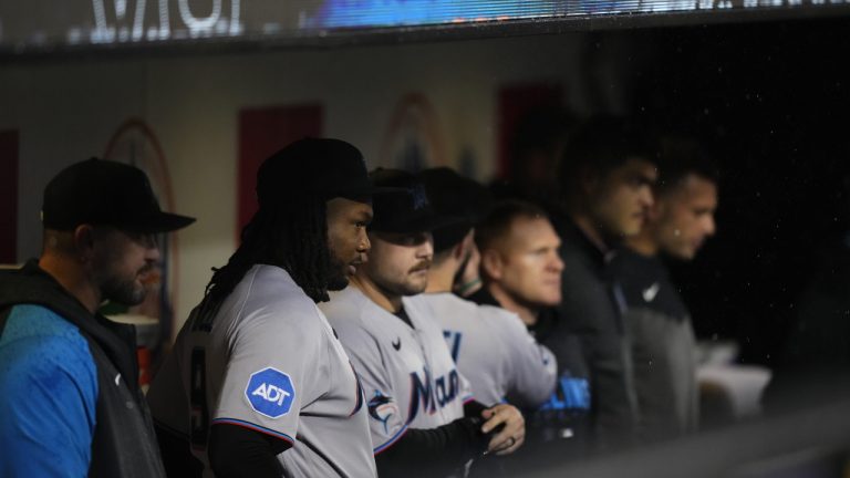 Miami Marlins' Josh Bell, second from left, stands with teammates as they watch the grounds crew members work on the field during a rain delay against the New York Mets early Friday, Sept. 29, 2023, in New York. (Frank Franklin II/AP)