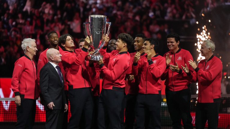 Team World's Taylor Fritz, fourth left, and Ben Shelton, centre, hoist the Laver Cup in front of their teammates, John McEnroe, back left, and Rod Laver, front left, after Team World defeated Team Europe 13-2 at the Laver Cup tennis tournament, in Vancouver, on Sunday, September 24, 2023. (Darryl Dyck/CP)