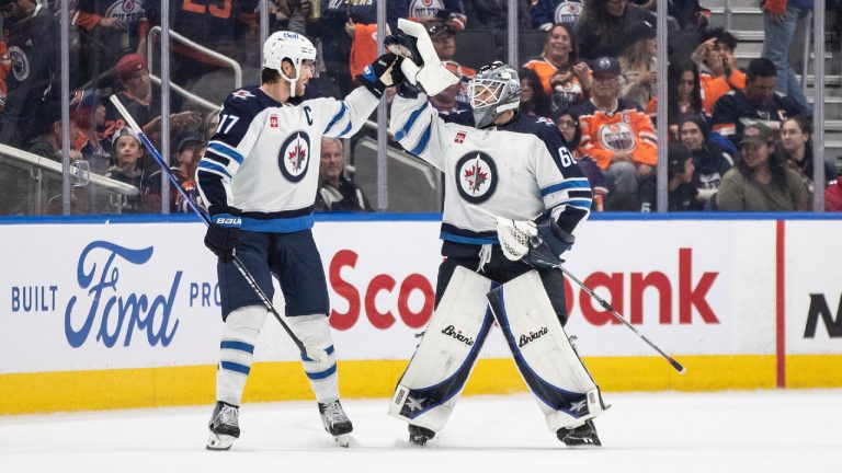Winnipeg Jets' Adam Lowry (17) and goalie Collin Delia (60) celebrate the overtime win against the Edmonton Oilers during shootout NHL preseason action in Edmonton on Sunday September 24, 2023. (Jason Franson/CP)