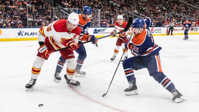 Calgary Flames' Nikita Zadorov (16) and Edmonton Oilers' Adam Erne (21) battle for the puck during second period NHL preseason action in Edmonton. (Jason Franson/THE CANADIAN PRESS)