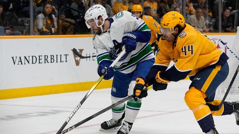Vancouver Canucks defenseman Mark Friedman (51) hits the puck away from Nashville Predators left wing Kiefer Sherwood (44) during the second period of an NHL hockey game Tuesday, Oct. 24, 2023, in Nashville, Tenn. (George Walker IV/AP Photo)