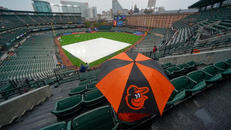 A fan sits in the stand with an umbrella as they wait for the start of Game 1 of an American League Division Series baseball game between the Baltimore Orioles and the Texas Rangers. (Julio Cortez/AP) (Julio Cortez/AP)