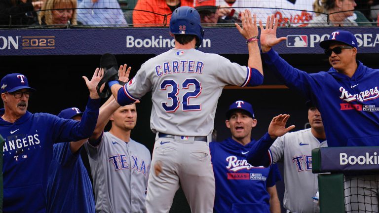 Texas Rangers center fielder Evan Carter (32) is greeted by teammates after scoring against the Baltimore Orioles during the fourth inning in Game 1 of an American League Division Series baseball game. (Julio Cortez/AP)
