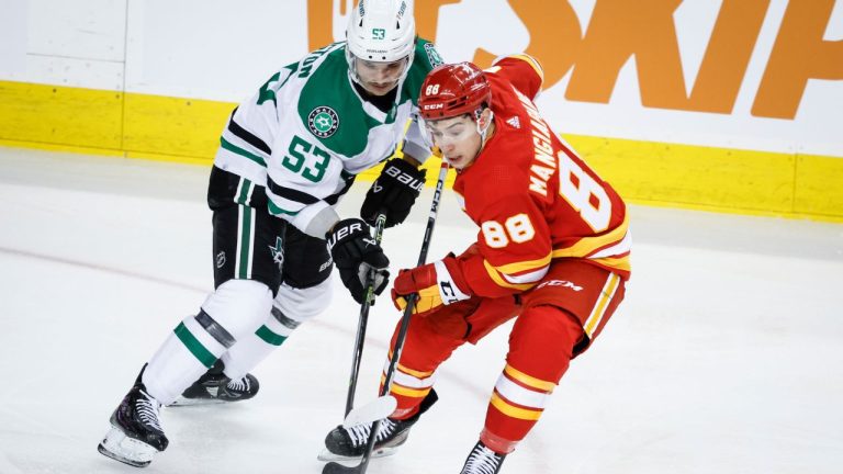 Dallas Stars forward Wyatt Johnston checks Calgary Flames forward Andrew Mangiapane during first period NHL hockey action in Calgary, Thursday, Nov. 30, 2023. (Jeff McIntosh/CP Photo)