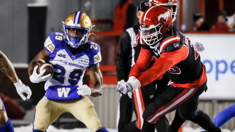 Winnipeg Blue Bombers running back Greg McCrae, left, gets away from Calgary Stampeders defensvie lineman Damontre Moore during first half CFL football action. (Jeff McIntosh/CP)