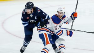 Oilers' captain Connor McDavid battles with Jets' captain Adam Lowry. (CP)