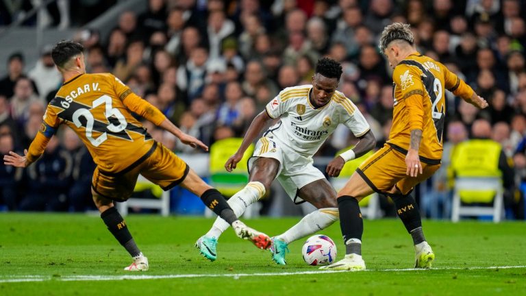 Real Madrid's Vinicius Junior, centre, duels for the ball with Rayo's Oscar Valentin, left, and Rayo's Andrei Ratiu during a Spanish La Liga soccer match between Real Madrid and Rayo Vallecano at the Santiago Bernabeu stadium in Madrid, Spain, Sunday, Nov. 5, 2023. (Manu Fernandez/AP)