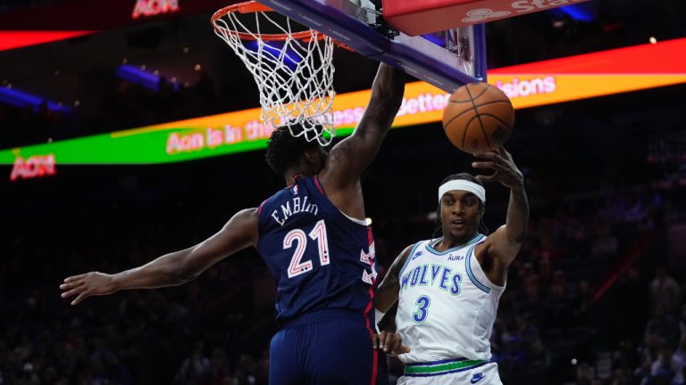 Minnesota Timberwolves' Jaden McDaniels, right, passes the ball around Philadelphia 76ers' Joel Embiid during the first half of an NBA basketball game, Wednesday, Dec. 20, 2023, in Philadelphia. (Matt Slocum/AP)