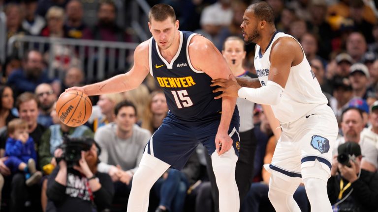 Denver Nuggets centre Nikola Jokic, left, looks to pass the ball as Memphis Grizzlies forward Xavier Tillman, right, defends in the second half of an NBA basketball game Thursday, Dec. 28, 2023, in Denver. (David Zalubowski/AP)