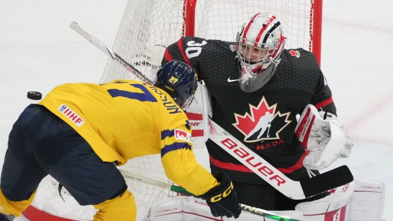 Canada goaltender Mathis Rousseau (30) keeps his eye on the puck following a shot by Sweden's Oskar Pettersson (27) during third period action at the IIHF World Junior Hockey Championship in Gothenburg, Sweden, Friday, Dec. 29, 2023. (CP)