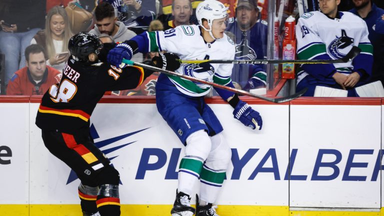 Vancouver Canucks defenceman Nikita Zadorov, right, swats away a check from Calgary Flames forward A.J. Greer during first period NHL hockey action in Calgary, Saturday, Dec. 2, 2023. (Jeff McIntosh/CP)