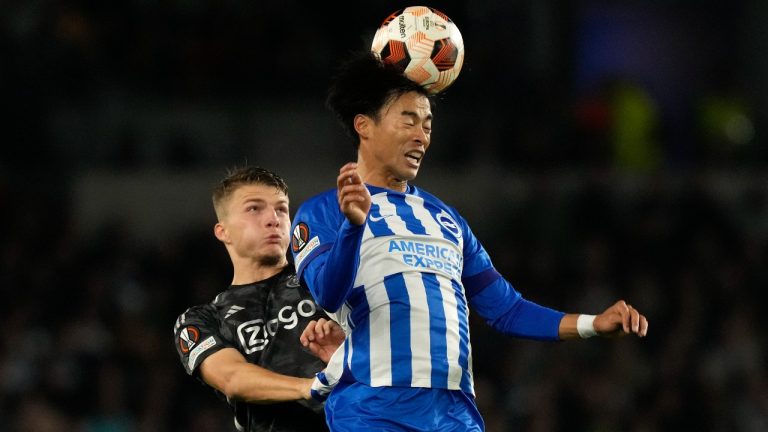 Brighton's Kaoru Mitoma, right, jumps for the ball with Ajax's Steven Berghuis during the Europa League Group B soccer match between Brighton and Hove Albion and Ajax at the Amex stadium in Brighton, England, Thursday, Oct. 26, 2023. (AP Photo/Frank Augstein)