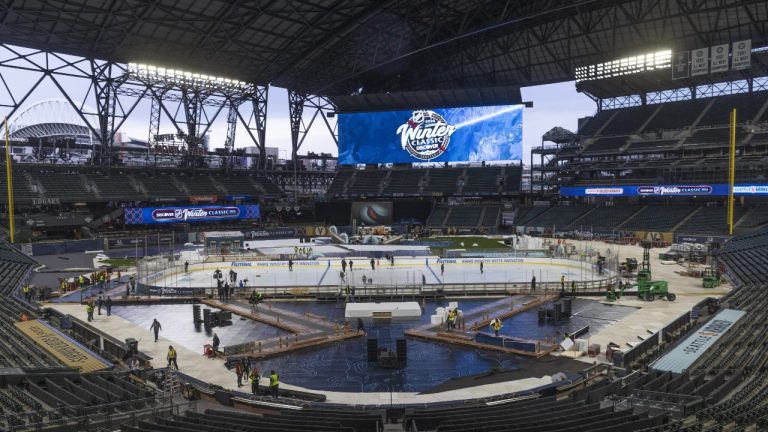 An ice crew adds lines and logos to the NHL Winter Classic ice skating rink at T-Mobile Park in Seattle Thursday, Dec. 28, 2023. The Seattle Kraken will fact the Las Vegas Golden Knights on Monday, Jan. 1, 2024. (Ellen M. Banner/The Seattle Times via AP)