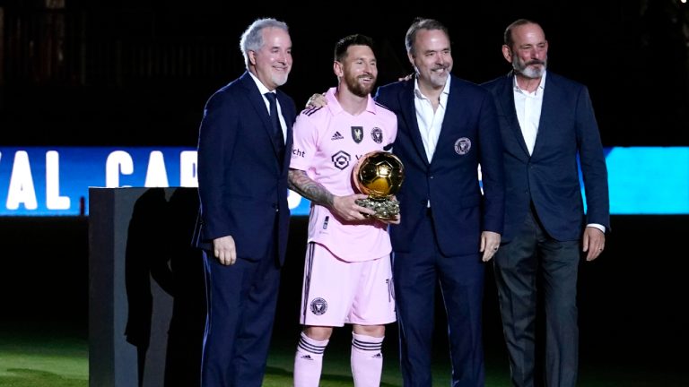 Inter Miami forward Lionel Messi, second form left, holds his Ballon d'Or trophy before the team's club friendly soccer match against New York City FC, Friday, Nov. 10, 2023, in Fort Lauderdale, Fla. Also pictured are Inter Miami managing owner Jorge Mas, left, Inter Miami co-owner Jose Mas, second from right, and MLS Commissioner Don Garber. (Lynne Sladky/AP)