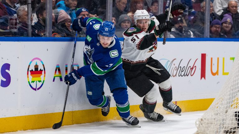 Vancouver Canucks' Nils Hoglander (21) and Arizona Coyotes' Troy Stecher (51) vie for the puck during the first period of an NHL hockey game in Vancouver on Thursday, Jan. 18, 2024. (Ethan Cairns/CP)