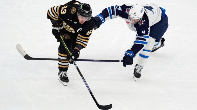 Winnipeg Jets' Neal Pionk (4) and Boston Bruins' Brad Marchand (63) battle for the puck during the first period of an NHL hockey game, Monday, Jan. 22, 2024, in Boston. (Michael Dwyer/AP)