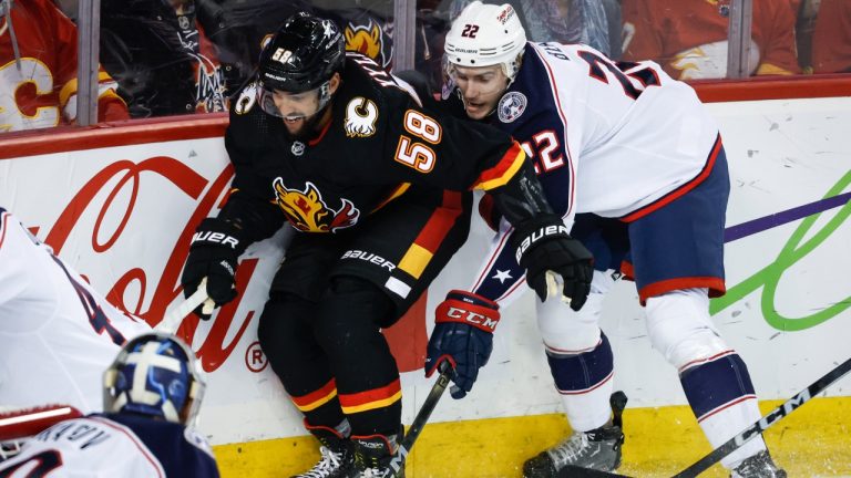 Columbus Blue Jackets defenceman Jake Bean (22) checks Calgary Flames defenceman Oliver Kylington (58) during first period NHL hockey action in Calgary, Thursday, Jan. 25, 2024. (Jeff McIntosh/CP)