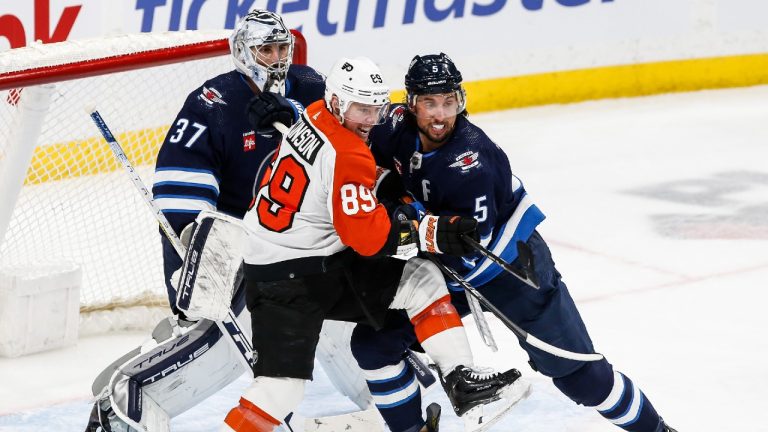 Winnipeg Jets' Brenden Dillon (5) defends against Philadelphia Flyers' Cam Atkinson (89) in from of goaltender Connor Hellebuyck (37) during second period NHL action in Winnipeg, Saturday, Jan. 13, 2024. (John Woods/CP)