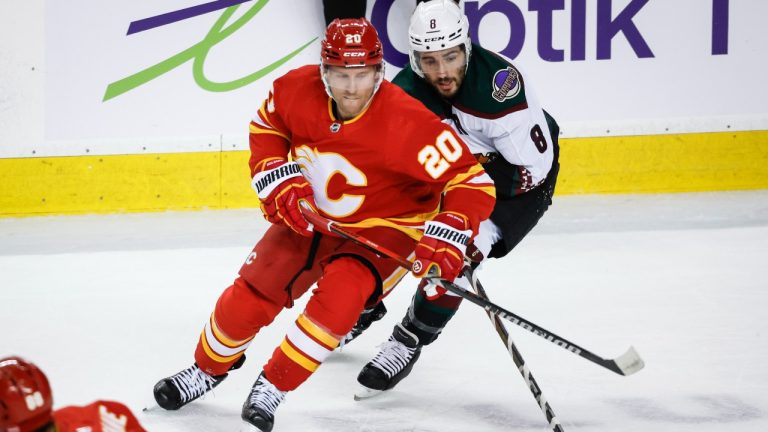 Arizona Coyotes forward Nick Schmaltz (8) is checked by Calgary Flames forward Blake Coleman (20) during first period NHL hockey action in Calgary, Tuesday, Jan. 16, 2024. (Jeff McIntosh/THE CANADIAN PRESS)