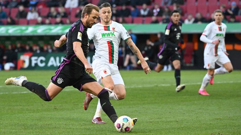 Munich's Harry Kane, left, and Augsburg's Jeffrey Gouweleeuw battle for the ball during the Bundesliga soccer match between FC Augsburg and Bayern Munich at the WWK-Arena, Augsburg, Germany, Saturday Jan. 27, 2024. (Sven Hoppe/dpa via AP)