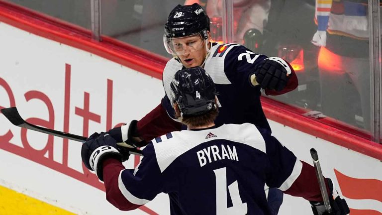 Colorado Avalanche defenseman Bo Byram (4) congratulates center Nathan MacKinnon, top, after MacKinnon scored in the second period of an NHL hockey game against the Arizona Coyotes, Sunday, Feb. 18, 2024, in Denver. (David Zalubowski/AP)