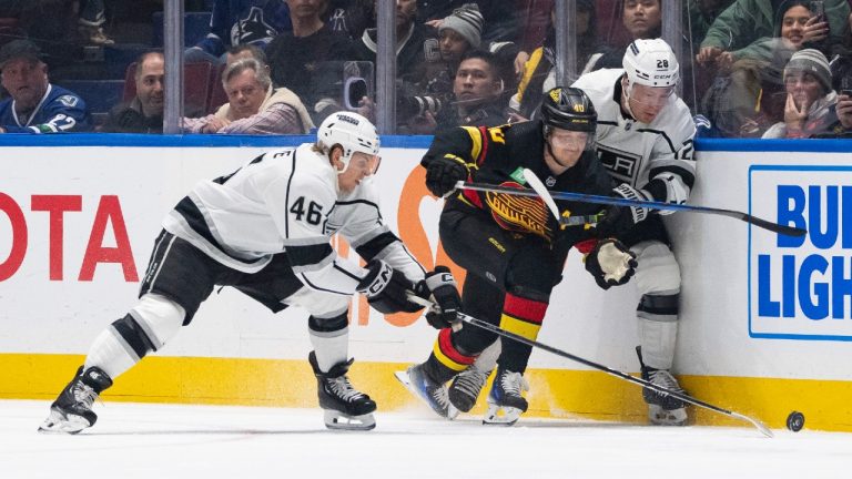 Los Angeles Kings' Blake Lizotte (46), left, Jaret Anderson-Dolan (28), right, and Vancouver Canucks' Elias Pettersson (40), middle, vie for the puck during the first period of an NHL hockey game in Vancouver, on Thursday, Feb. 29, 2024. (Ethan Cairns/CP)