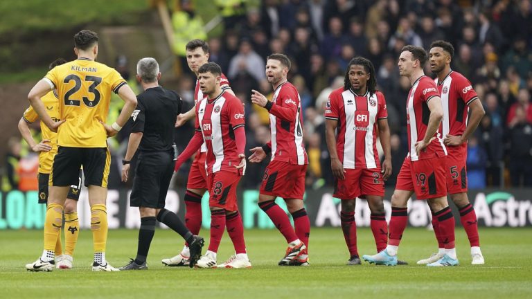 Match referee Darren Bond speaks with the Sheffield United players following an altercation between Sheffield United's Jack Robinson, second right and teammate Anel Ahmedhodzic, fourth left, during the English Premier League soccer match between Wolverhampton Wanderers and Sheffield United, at Molineux Stadium, in Wolverhampton, England, Sunday, Feb. 25, 2024. (Mike Egerton/PA via AP)