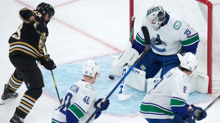 Boston Bruins left wing Brad Marchand, left, scores as Vancouver Canucks goaltender Thatcher Demko, top right, is unable to block the shot during the first period of an NHL hockey game. (Steven Senne/AP)