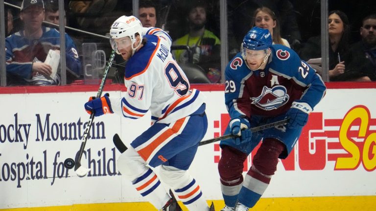 Edmonton Oilers centre Connor McDavid, left, collects the puck as Colorado Avalanche centre Nathan MacKinnon, right, pursues in the second period of an NHL hockey game Sunday, Feb. 19, 2023, in Denver. (David Zalubowski/AP)