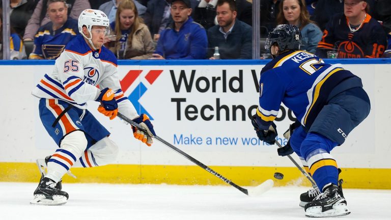 Edmonton Oilers' Dylan Holloway (55) passes the puck while under pressure from St. Louis Blues' Matthew Kessel (51) during the first period of an NHL hockey game Thursday, Feb. 15, 2024, in St. Louis. (Scott Kane/AP Photo)