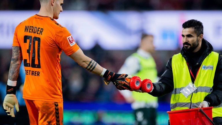 Bremen goalkeeper Michael Zetterer hands a steward a remote-controlled car from the pitch during the Bundesliga soccer match between FC Koln and Werder Bremen at RheinEnergieStadion, Cologne, Germany, Friday Fab. 16, 2024. (Rolf Vennenbernd/dpa via AP)