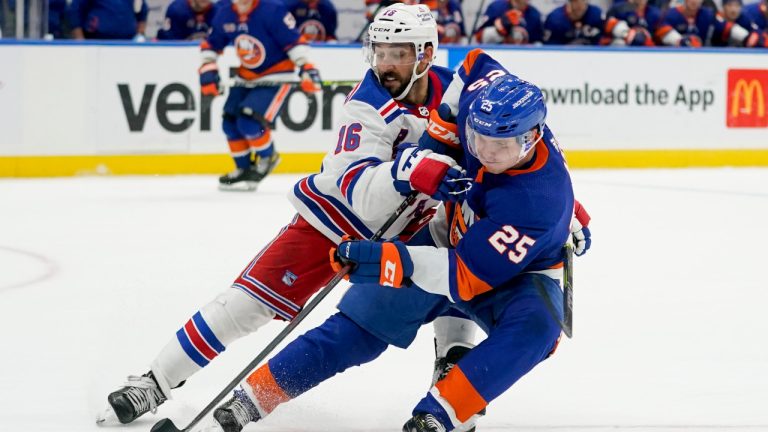 New York Islanders defenceman Sebastian Aho (25) and New York Rangers center Vincent Trocheck (16) battle for the puck in the third period of an NHL hockey game, Wednesday, Oct. 26, 2022, in Elmont, N.Y. The Islanders won 3-0. (AP Photo/John Minchillo)