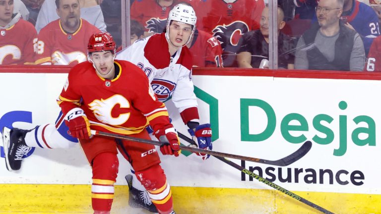 Montreal Canadiens' Juraj Slafkovsky, right, battles at the boards with Calgary Flames' Andrew Mangiapane during first period NHL hockey action in Calgary, Alta., Saturday, March 16, 2024. (Larry MacDougal/CP)
