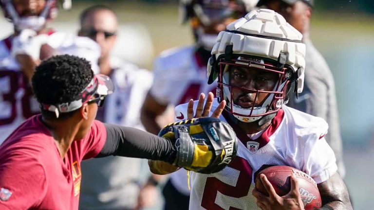 Washington Commanders running back J.D. McKissic, right, runs wearing a Guardian Cap football helmet during practice at the team's NFL football training facility, Wednesday, July 27, 2022 in Ashburn, Va. (Alex Brandon/AP)