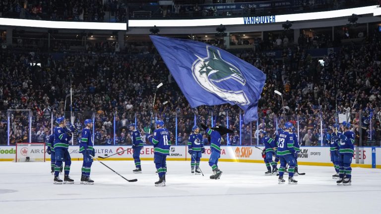 Vancouver Canucks players gather at centre ice to raise their sticks to the fans after defeating the Calgary Flames during their final NHL regular season home hockey game, in Vancouver, on Tuesday, April 16, 2024. (Darryl Dyck/CP)