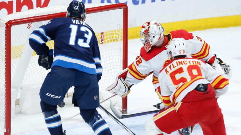 Winnipeg Jets' Gabriel Vilardi (13) scores on Calgary Flames goaltender Dustin Wolf (32) as Oliver Kylington (58) defends during first period NHL action in Winnipeg on Thursday, April 4, 2024. THE CANADIAN PRESS/John Woods