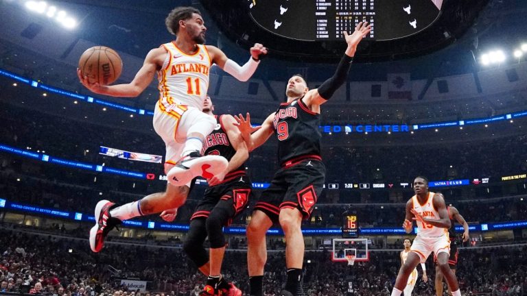 Atlanta Hawks guard Trae Young, left, looks to pass against Chicago Bulls guard Alex Caruso and center Nikola Vucevic, right, during the first half of an NBA basketball play-in tournament game in Chicago, Wednesday, April 17, 2024. (AP Photo/Nam Y. Huh)