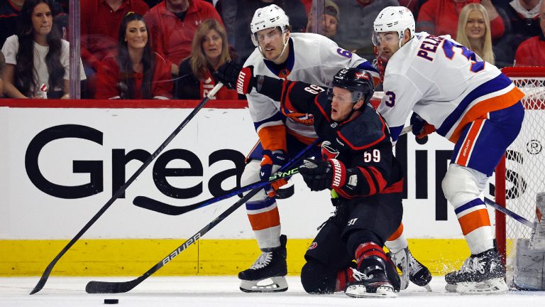 Carolina Hurricanes' Jake Guentzel (59) tries to gather in the puck between New York Islanders' Ryan Pulock (6) and Adam Pelech (3) during the first period in Game 1 of an NHL hockey Stanley Cup first-round playoff series in Raleigh, N.C., Saturday, April 20, 2024. (Karl B DeBlaker/AP)