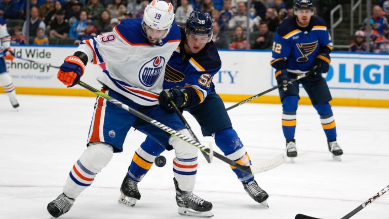 Edmonton Oilers' Adam Henrique (19) and St. Louis Blues' Zach Dean (52) battle for a loose puck during the first period of an NHL hockey game Monday, April 1, 2024, in St. Louis. (Jeff Roberson/AP)