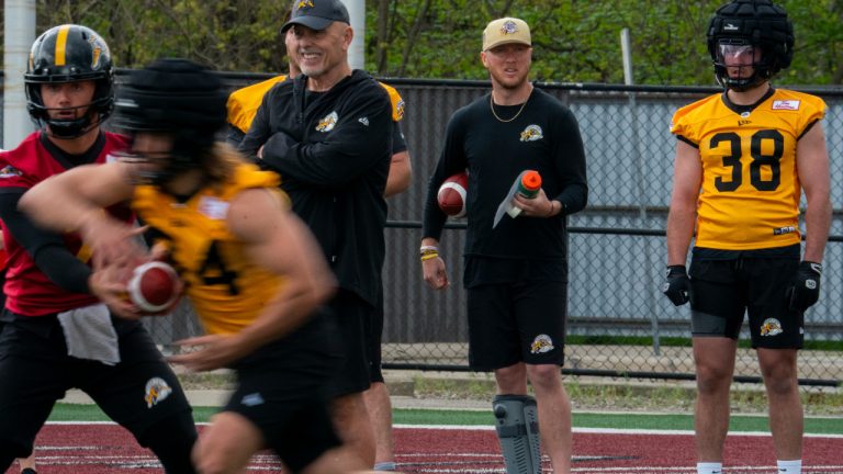 Hamilton Tiger Cats quarterback Bo Levi Mitchell (19) wears a boot cast while teammates run plays during the first day of training camp at Ron Joyce Stadium at McMaster University, in Hamilton, Ont., Sunday, May 12, 2024. (Peter Power/CP)