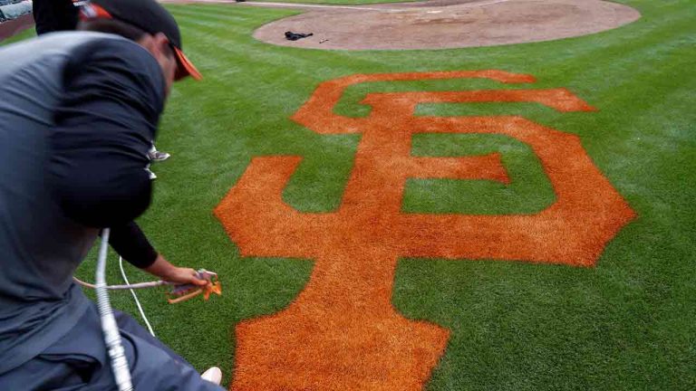 Grounds crew member Josh Warstler paints the San Francisco Giants' logo on stadium grass after the Giants played the Arizona Diamondbacks in a spring training baseball game Sunday, March 2, 2014, in Scottsdale, Ariz. (Gregory Bull/AP)