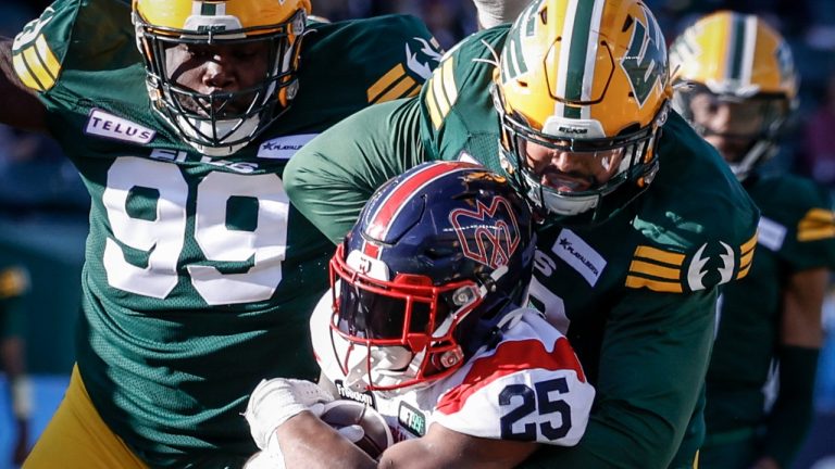 Montreal Alouettes running back Walter Fletcher, left, is tackled by Edmonton Elks defensive lineman Peter Adjey during second half CFL football action in Edmonton, Saturday, Oct. 14, 2023. (Jeff McIntosh/CP)