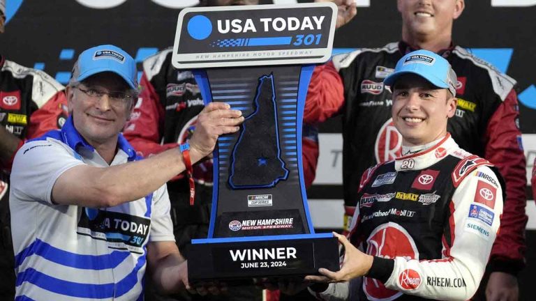 Howard Altschiller, left, executive editor of Seacoast Media Group, presents Christopher Bell, right, with the winner's trophy during ceremonies after Bell won the NASCAR Cup Series race. (Steven Senne/AP)
