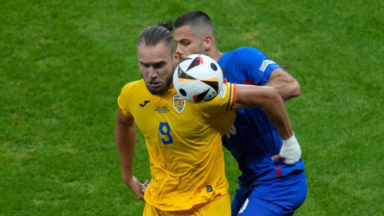 Romania's George Puscas, left, and Slovakia's David Hancko battle for the ball during a Group E match at the Euro 2024 soccer tournament in Frankfurt, Germany, Wednesday, June 26, 2024. (Darko Vojinovic/AP Photo)