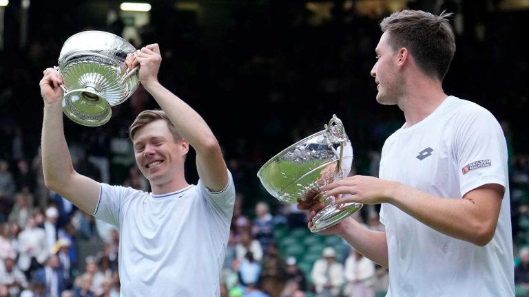 Harri Heliovaara of Finland, left, and playing partner Henry Patten of Britain celebrate to the crowd as they hold up their trophies after they defeated Australia's Max Purcell and compatriot Jordan Thompson on Centre Court in the men's doubles final at the Wimbledon tennis championships in London, Saturday, July 13, 2024. (Mosa'ab Elshamy/AP)